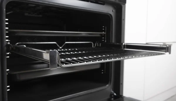 New modern electric oven built in black with screen, convention and grill, empty and open. Telescopic guides. Scandinavian style in a white minimalistic kitchen.