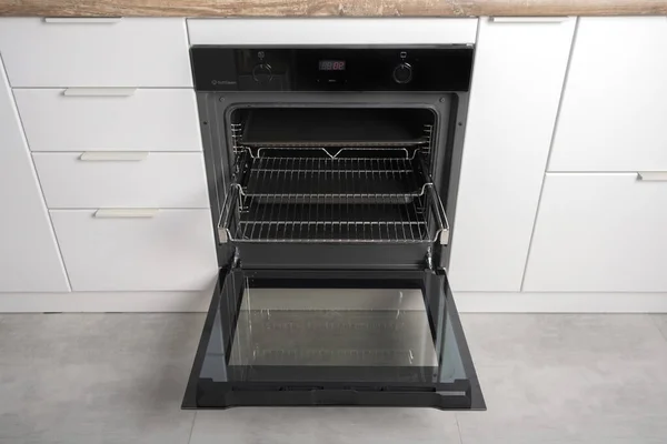 Nuovo forno elettrico moderno costruito in nero con schermo, convenzione e grill, vuoto e aperto. Guide telescopiche. Stile scandinavo in una cucina minimalista bianca. — Foto Stock