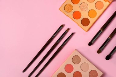 Bir grup nesne göz fonu paleti üzerinde pembe arkaplan görünümünde fotokopi alanı ile. Makyaj fırçası, yüz için dekoratif makyaj malzemesi. Dümdüz kadın aksesuarları vardı. Yüksek kalite fotoğraf. Kimse..
