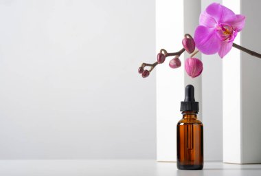 Mockup kozmetik yüz serumu kahverengi cam şişe üzerinde pipeti olan şık, minimalist beyaz arka plan geometrik dekor ve orkide çiçekleri olan. Kadın güzellik konsepti, boş şablon. Boşluğu kopyala