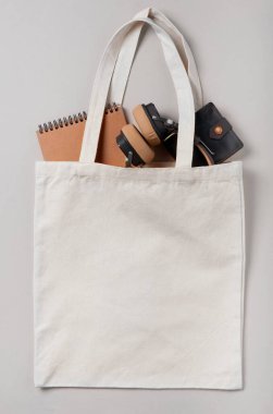 Tasarımınız için beyaz krema poşeti modeli boş, çevre dostu, fotokopi alanı ile sıfır atık. Minimalizm düzdü. İçinde kulaklıklar, bir defter ve bir erkek cüzdanı var..
