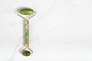 Fotokopi uzayı düzlüklü mermer beyaz arka planda yüz masajı için Jade silindiri. Yaş, kaldırma ve tonlama tedavisi, akupres