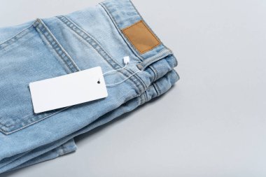 Gri arka planda uygun mavi kot üzerine boş, kirli deri etiketin, tasarımınız, logonuz ve reklamınız için uygun fotokopi alanının boş detaylı yakın plan görüntülerini oluşturun. Örnek. Düz yatıyordu.