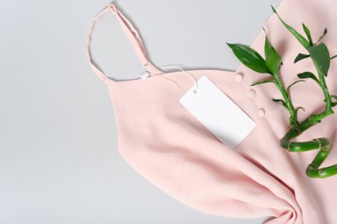 Tasarımınızı yerleştirmek için beyaz giysi etiketi, boş model şablonu. Gri arka planda kaliteli pamuklu pembe bir bluz. Bambu.
