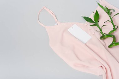 Tasarımınızı yerleştirmek için beyaz giysi etiketi, boş model şablonu. Gri arka planda kaliteli pamuklu pembe bir bluz. Bambu. Düz metin kopyalama alanı