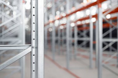 Bir depoda ya da fabrikada endüstriyel metal raflar var. Turuncu kirişli çelik yapı ve metal verimli depolama sistemi. Lojistik endüstriyel tasarım kavramları.