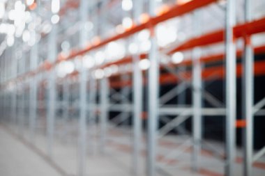 Bulanık odaklı endüstriyel arka plan metal raf rafları bir depo veya fabrikada. Turuncu kirişli çelik yapı ve metal verimli depolama sistemi. Lojistik endüstriyel tasarım kavramları.