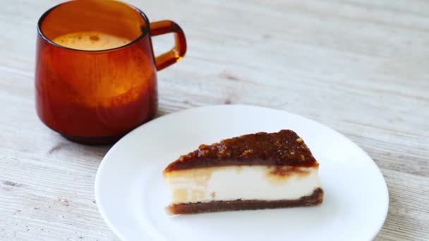 Het meisje zet een kwarktaart met pecannoten op tafel naast een kop koffie, legt een lepel als dessert op de hoer. — Stockvideo