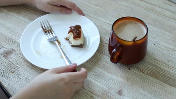Dziewczyna kroi kawałek sernika widelcem i je na śniadanie. — Wideo stockowe