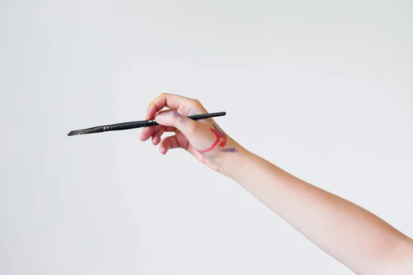 A mão de uma artista feminina segura um pincel para pintar em um fundo branco. — Fotografia de Stock