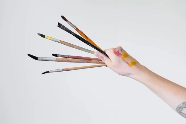 Рука дівчини-художниці тримає пензлик для малювання на білому тлі . Ліцензійні Стокові Зображення