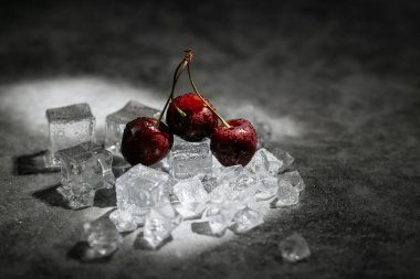 Koyu arkaplanda olgun, soğuk kırmızı kirazlar.