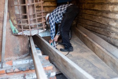 Köyde bir adam elektrikli testereyle ağaç kesiyor.