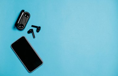 mavi arkaplanda kablosuz bluetooth kulaklık ve telefon