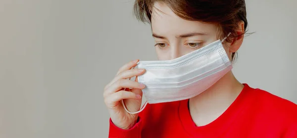 Girl puts on a medical mask on a white background — Stock Photo, Image
