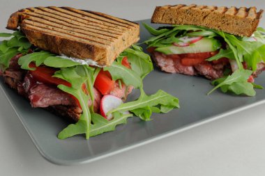 Ekmek üzerine ekmek, otlar, et ve sebzeler beyaz tabakta beyaz bir tabakta