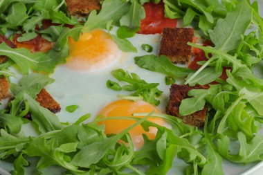 Beyaz arka planda beyaz bir tabakta yeşil ve kızarmış yumurtalar.