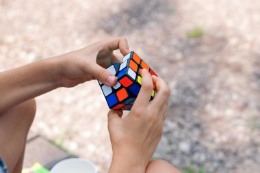 Moskova, 17 Temmuz 2021. Bir çocuk elinde bir Rubiks küp yapbozu tutuyor ve doğada topluyor, bir çocuğun ellerine yakın plan.