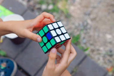 Moskova, 17 Temmuz 2021. Bir çocuk elinde bir Rubiks küp yapbozu tutuyor ve doğada topluyor, bir çocuğun ellerine yakın plan.