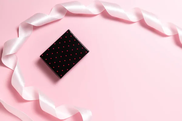 Małe pudełko i różowa wstążka na prezent zawijania na różowym tle — Zdjęcie stockowe