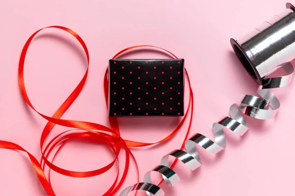 Małe pudełko, czerwona i srebrna wstążka na prezent zawijania na różowym tle — Zdjęcie stockowe