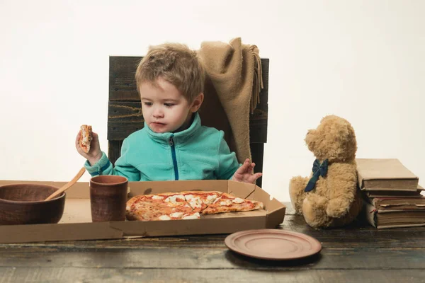 Çocuk pizza yiyor. Öğle yemeği, akşam yemeği, yemek konsepti. Mutfakta tatlı üzgün bir çocuk var.. — Stok fotoğraf