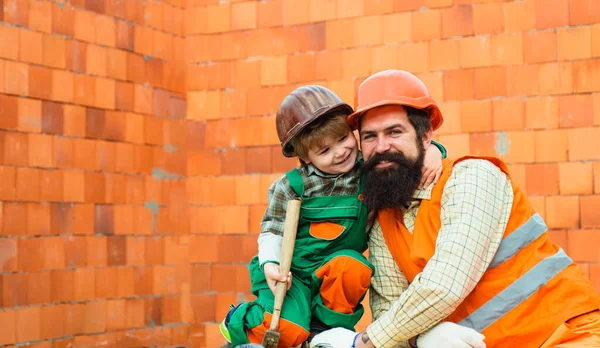 Χαρούμενο οικογενειακό εργαλείο. Πατέρας και γιος δουλεύουν μαζί σε ένα εργοτάξιο. Ο μικρός γιος βοηθάει τον πατέρα του με την οικοδομή. Εργασία αγοριών που εργάζονται στην κατασκευή εμπορικών κτιρίων. — Φωτογραφία Αρχείου