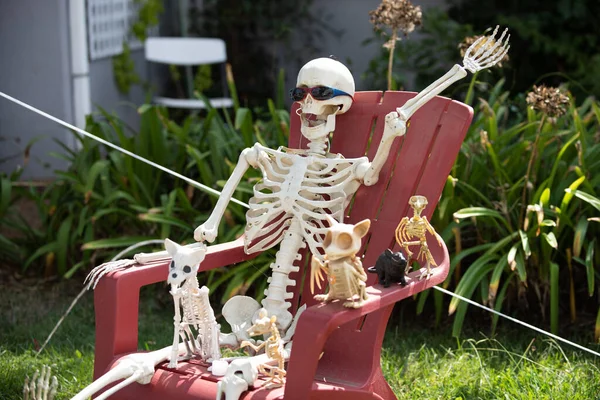 A família de esqueletos relaxa em uma cadeira no jardim. Decorações de outubro de Halloween. — Fotografia de Stock