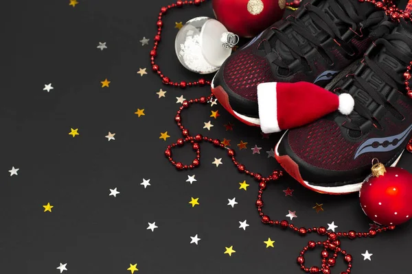 Siyah arka planda altın ve gümüş yıldızlı konfeti olan siyah bir spor ayakkabısı ve Noel süslemeleri vardı. Yeni yıl ve Noel konsepti. Kopyalama alanı