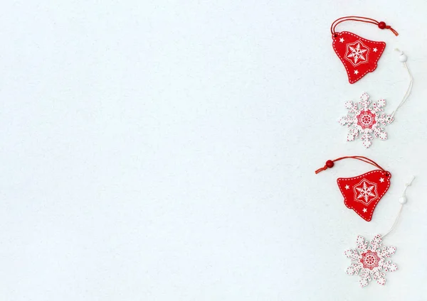 Noel ve yeni yıl arkaplanı ev yapımı kırmızı çanlar ve ağaçtan beyaz kar taneleri. Metinleriniz için bir yeri olan beyaz arkaplanda tatil simgeleri.