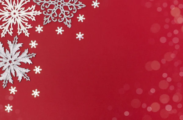Yılbaşı ve yeni yıl arkaplanı, kar taneleri süslemeleri. Kırmızı arka planda noel tebrik kartı kopyalama alanı var. Üst manzara, düz uzanma.