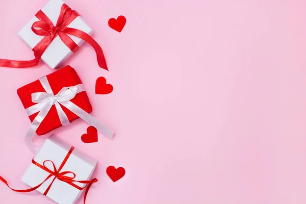 Composición del día de San Valentín con caja de regalo, corazones brillantes de papel y cinta sobre fondo rosa. Tarjeta de felicitación maqueta. Plano, vista superior, espacio para copiar. Imágenes de stock libres de derechos