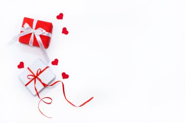 Şenlikli fiyonklu hediye kutuları ve beyaz arka planda küçük keçeli kalpler. Düz konum, üst görünüm, kopyalama alanı. Sevgililer Günü afişi ya da tebrik kartı