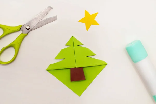 Step-by-step instructions for making Christmas Tree Corner Bookmarks. DIY. Creative origami ideas for kids. Top view, flat lay. Step 5 - cut the Christmas tree shape