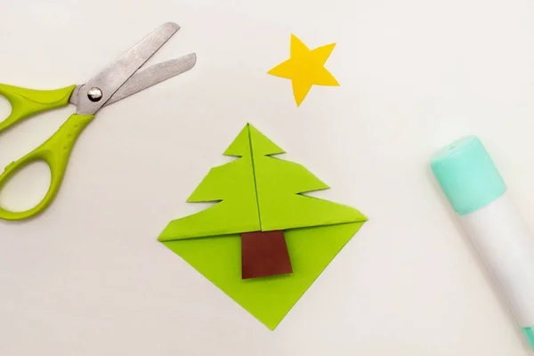 Instrucciones paso a paso para hacer marcadores de esquina del árbol de Navidad. Bricolaje. Ideas creativas de origami para niños. Vista superior, cama plana. Paso 5 - cortar la forma del árbol de Navidad Imagen de stock