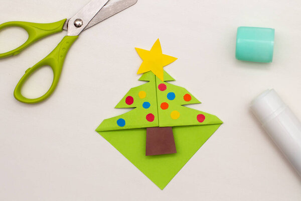 Step-by-step instructions for making Christmas Tree Corner Bookmarks. DIY. Creative origami ideas for kids. Top view, flat lay. Step 6 - decorate with colored paper baubles