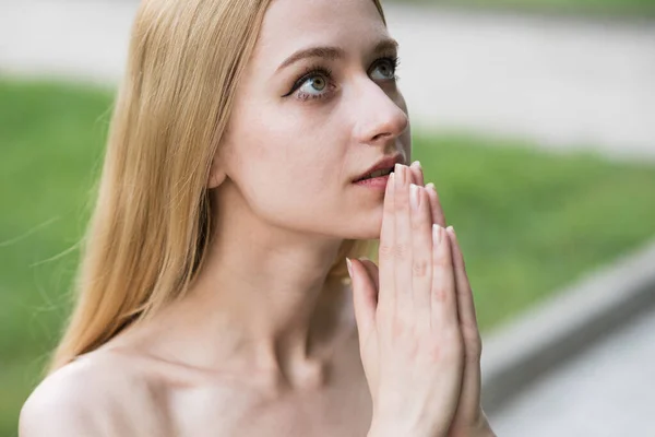 Portrait of a spiritual, young and attractive blonde girl. Lady pray to God with hope and faith