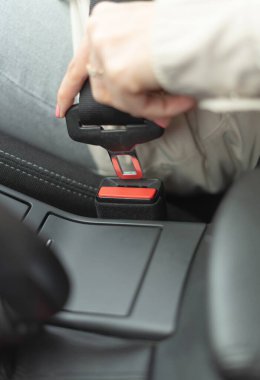 Bir kadın araba kullanmadan önce emniyet kemeri takar..