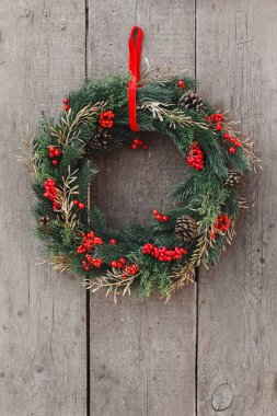 Tahta arka planda kırmızı böğürtlenli Noel çelengi. Noel dekoru ev yapımı