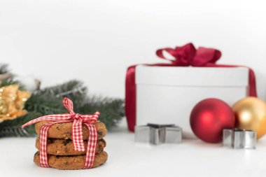 Beyaz arka planda ev yapımı kurabiyeler, kurdeleli hediye kutusu, köknar dalı, toplar. Yeni yıl kartı.