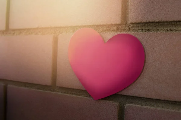 An einer braunen Ziegelwand hängt ein Aufkleber in Form eines scharlachroten Herzens. Kopierraum — Stockfoto