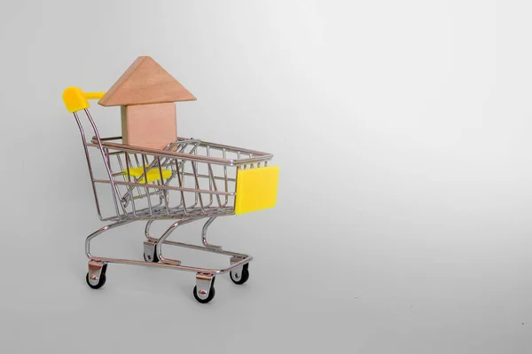 灰色の背景に黄色のハンドルを持つ食料品のカートで木製のキューブで作られた家モデル サイドビュー テキストの場所 — ストック写真