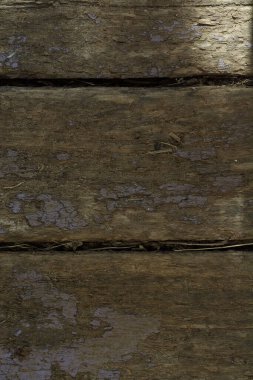 Eski tahta tahtaların arka planı. Güneş lekelerindeki eski tahtaların çatlak dokusu. Yakın plan. Dikey format. Metin için yer