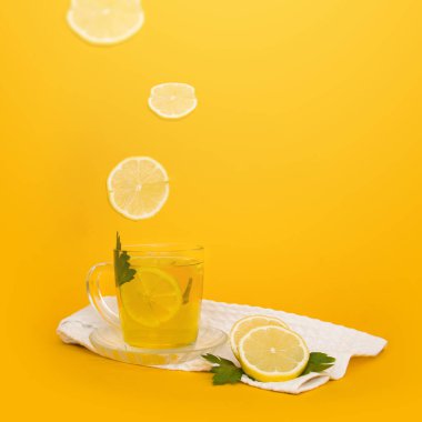 Limon dilimleri lezzetli, ferahlatıcı bir içecekle bardağa düşer. Bir bardak limonata, beyaz havlu ve limonla birlikte. Kare biçiminde. Metin için yer