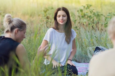 Açık alanda meditasyondan ve yogadan önce doğada konuşan genç kadınlar. Fitness konsepti, ruhani uygulama, psikolojik yardım, kadın arkadaşlığı. Kopyalama alanı