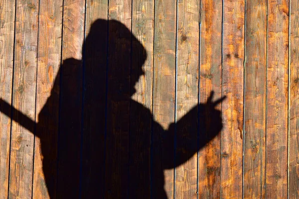 silhouette of a man on a wall of wooden planks