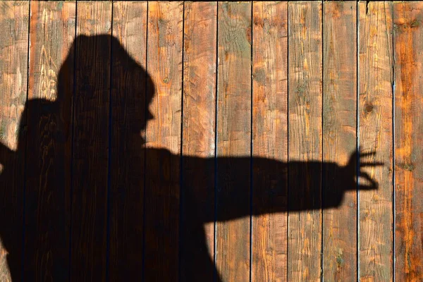 silhouette of a man on a wall of wooden planks