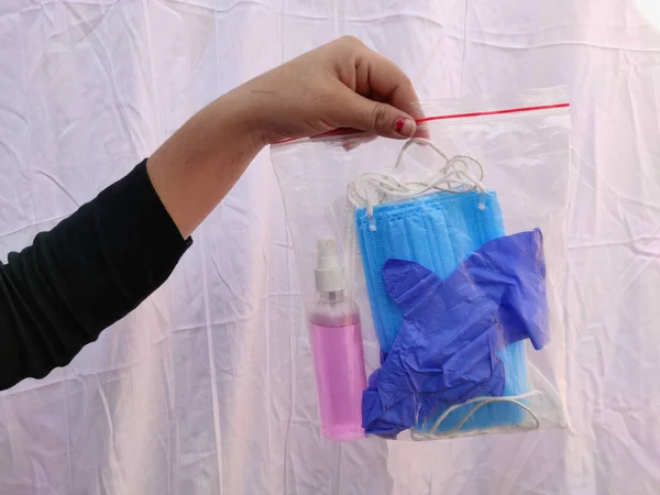 Kit de prevención de virus covid contiene mascarilla facial desinfectante mano y guantes quirúrgicos paquete de agarre por la mujer en la mano — Foto de Stock