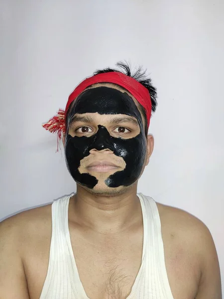 Young man with a black charcoal mask on his face on white background, Young and beautiful man with black peel-off mask on her face, — Stock Photo, Image
