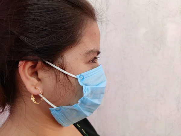 Seitenansicht der jungen indischen Frau Gesicht trägt medizinische Gesichtsmaske auf weißem Hintergrund. Schützen Sie Ihre Gesundheit. Coronavirus-Konzept — Stockfoto